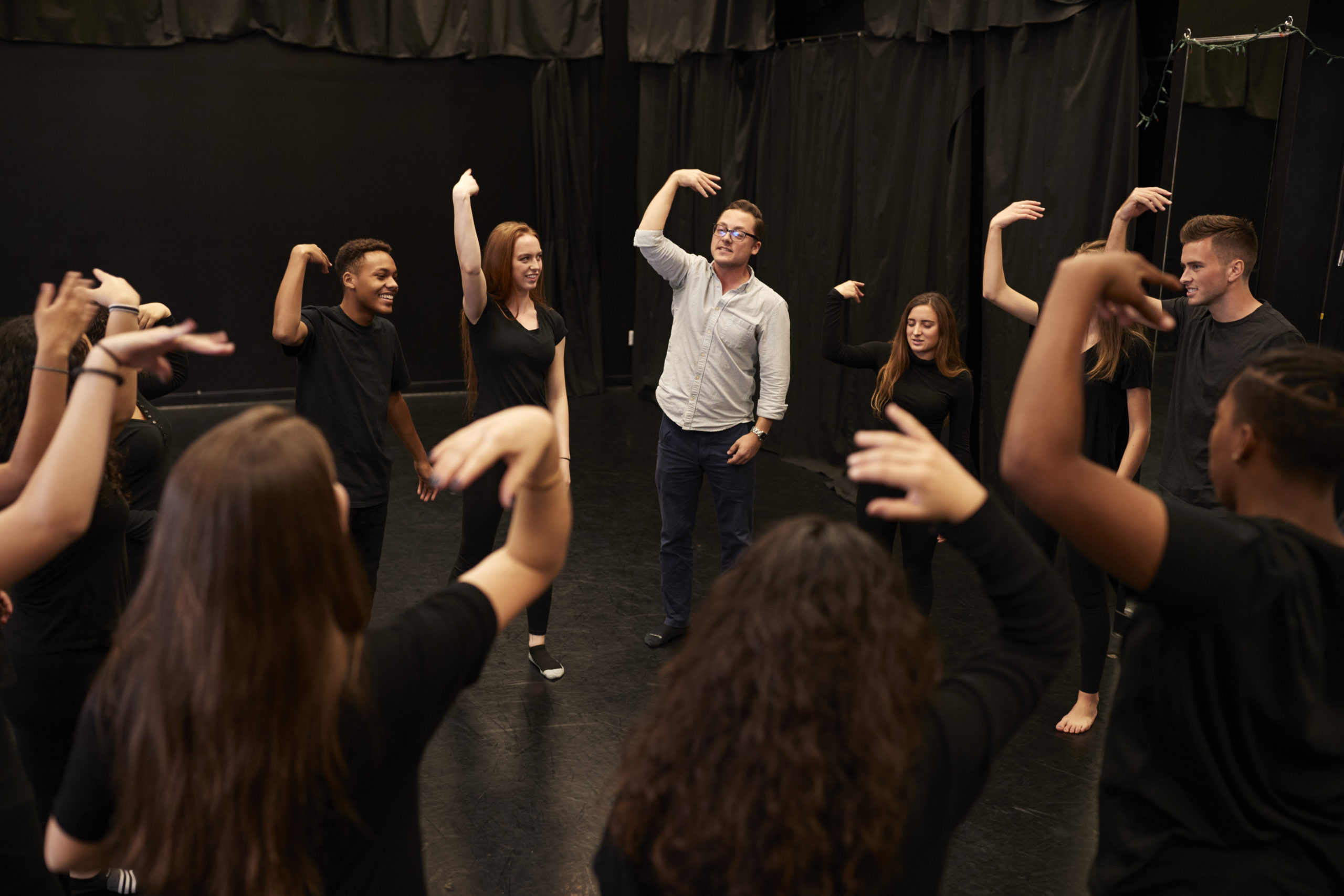 Teacher With Male And Female Drama Students At Performing Arts School In Studio Improvisation Class